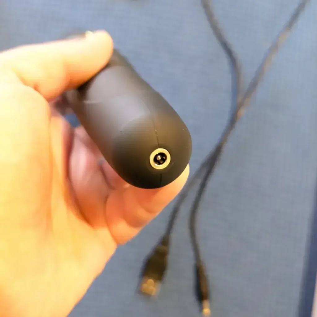Base of the Lovense Domi 2 showing the round charging port, with the USB charging cable behind it