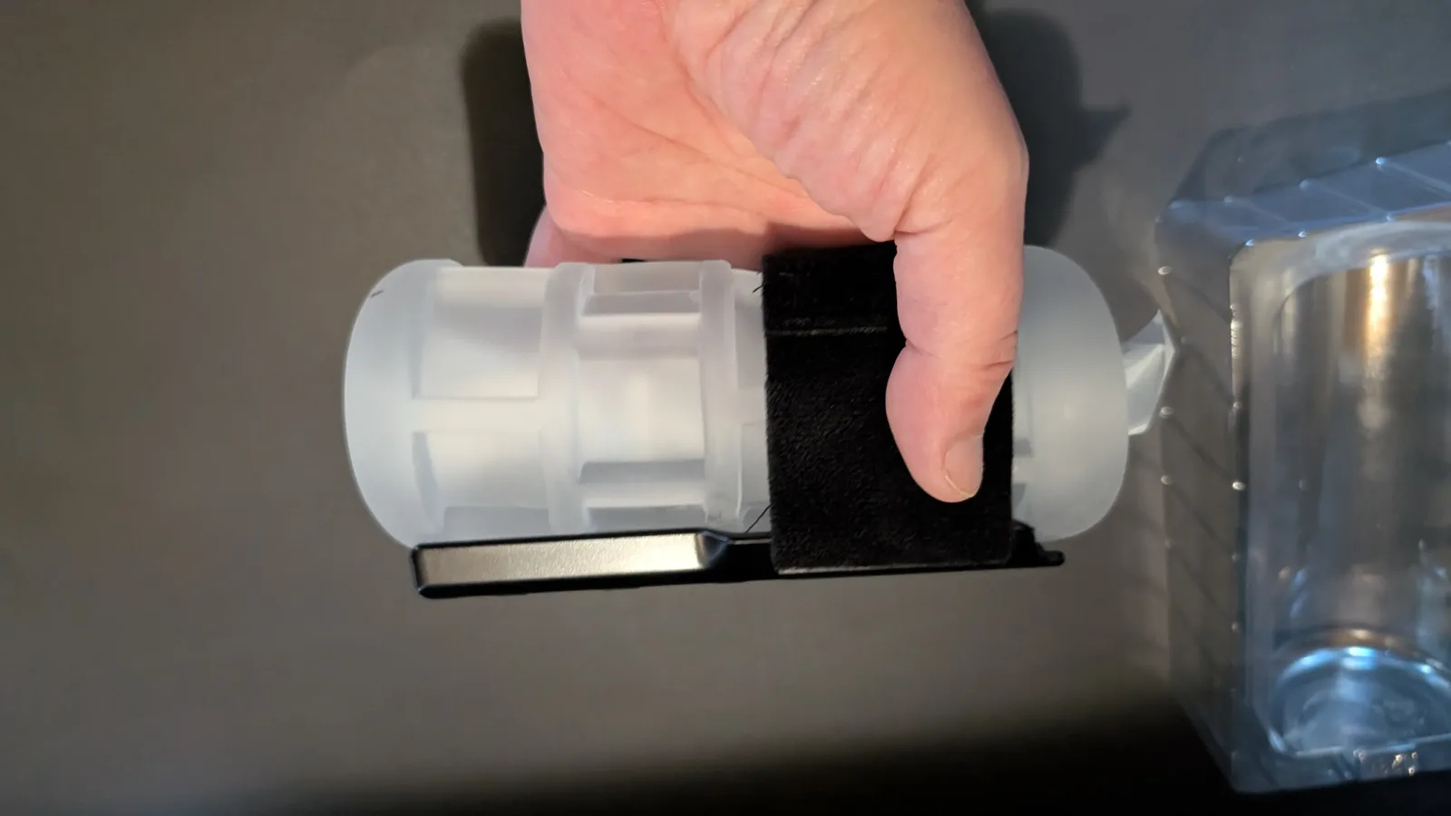 Hand gripping the Solace Pro Grip Kit, with the holder along the underside and the band across the sleeve